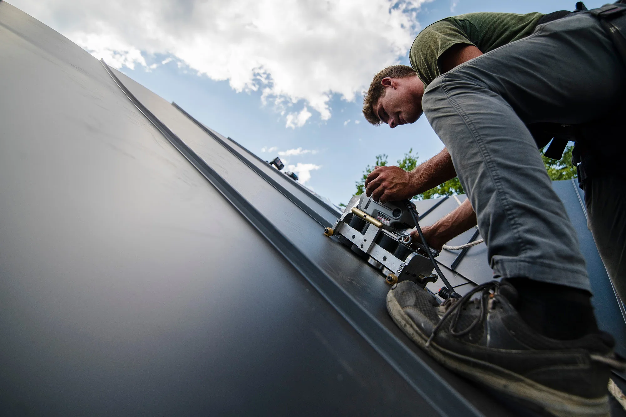 A Mantle Roofing professional operating a seaming machine on a standing-seam metal roof