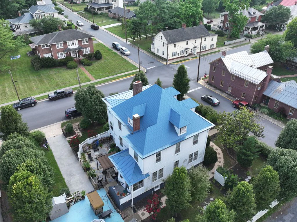 Aerial view of completed blue metal shingles and standing seam roof sections on a Strasburg, Virginia home